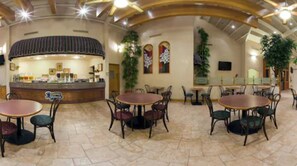 A spacious indoor area with multiple round tables and chairs, a counter with a striped awning, and decorative plants. - Holiday Inn Express Chihuahua by IHG (Chihuahua)