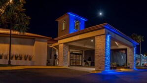 A hotel entrance with a stone facade, a blue-lit tower, and a clear sky. - Holiday Inn Express Chihuahua by IHG (Chihuahua)