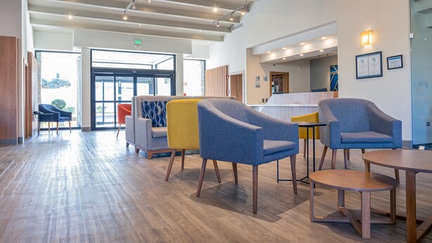 A modern lobby with a reception desk, seating area with armchairs, and a wooden floor. - Holiday Inn Express Chihuahua by IHG (Chihuahua)