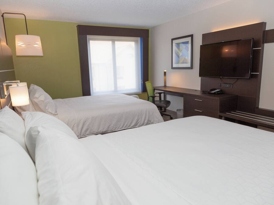Habitación de hotel con dos camas, un escritorio, una silla, un televisor y una ventana.
