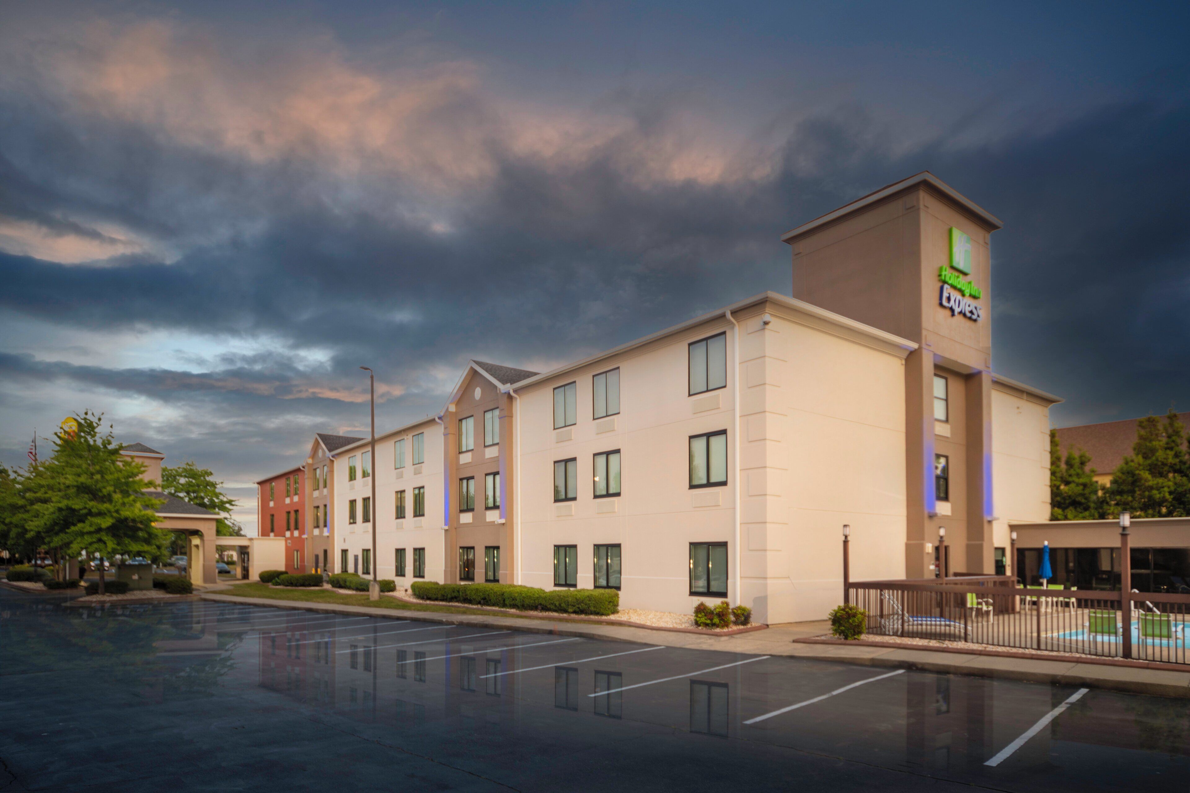 A multi-story hotel with a flat roof, large windows, and a parking lot in front.