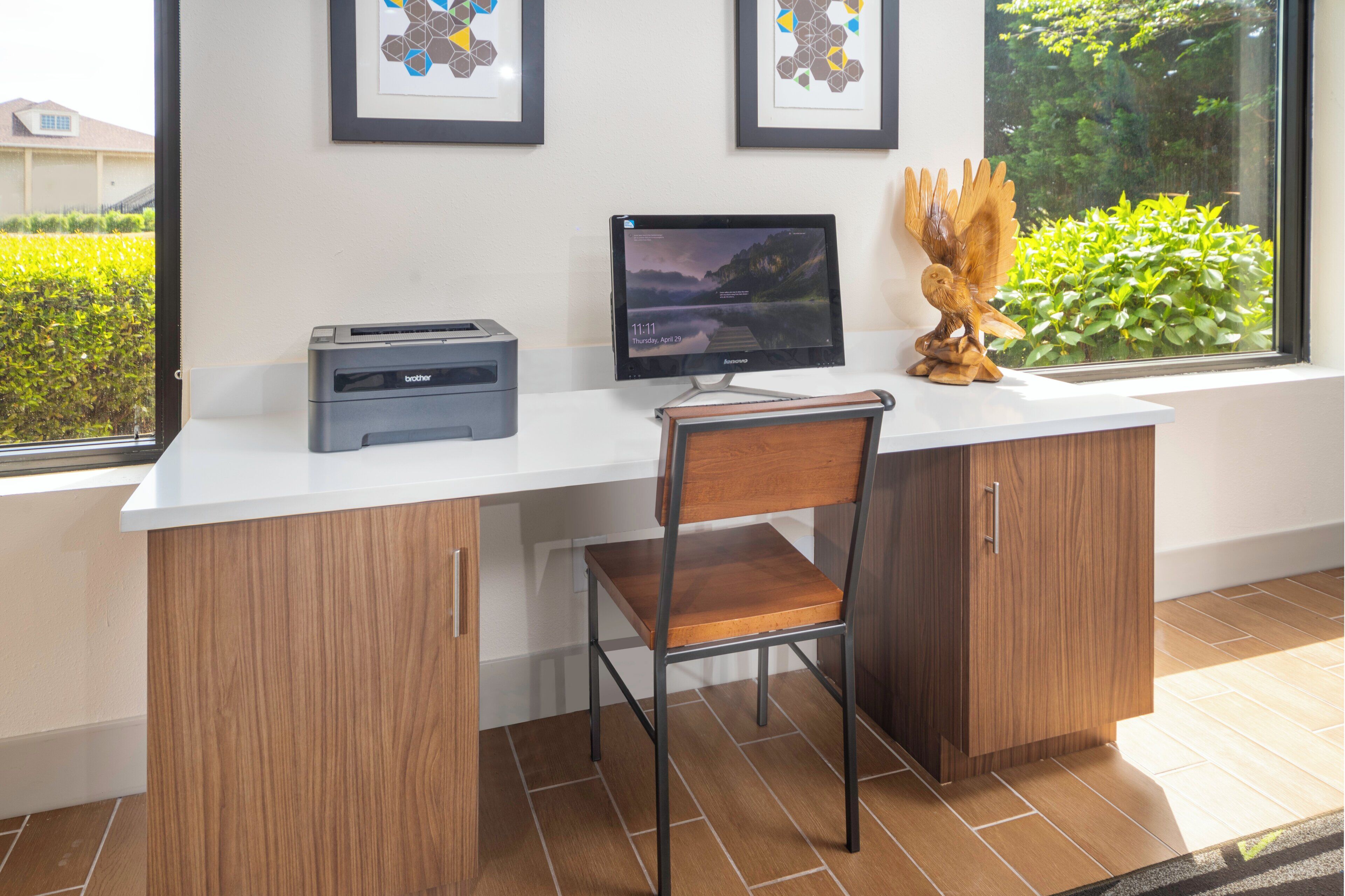 Un espacio de trabajo con escritorio, silla, monitor de computadora, impresora y objetos decorativos.