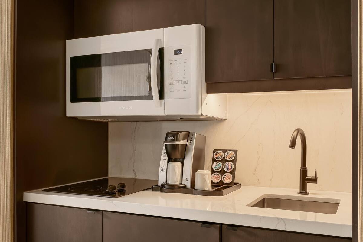 A compact kitchen with a microwave, coffee maker, and a sink.