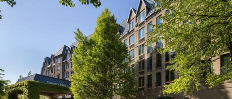 A multi-story hotel with a covered entrance, large windows, and a well-maintained lawn.