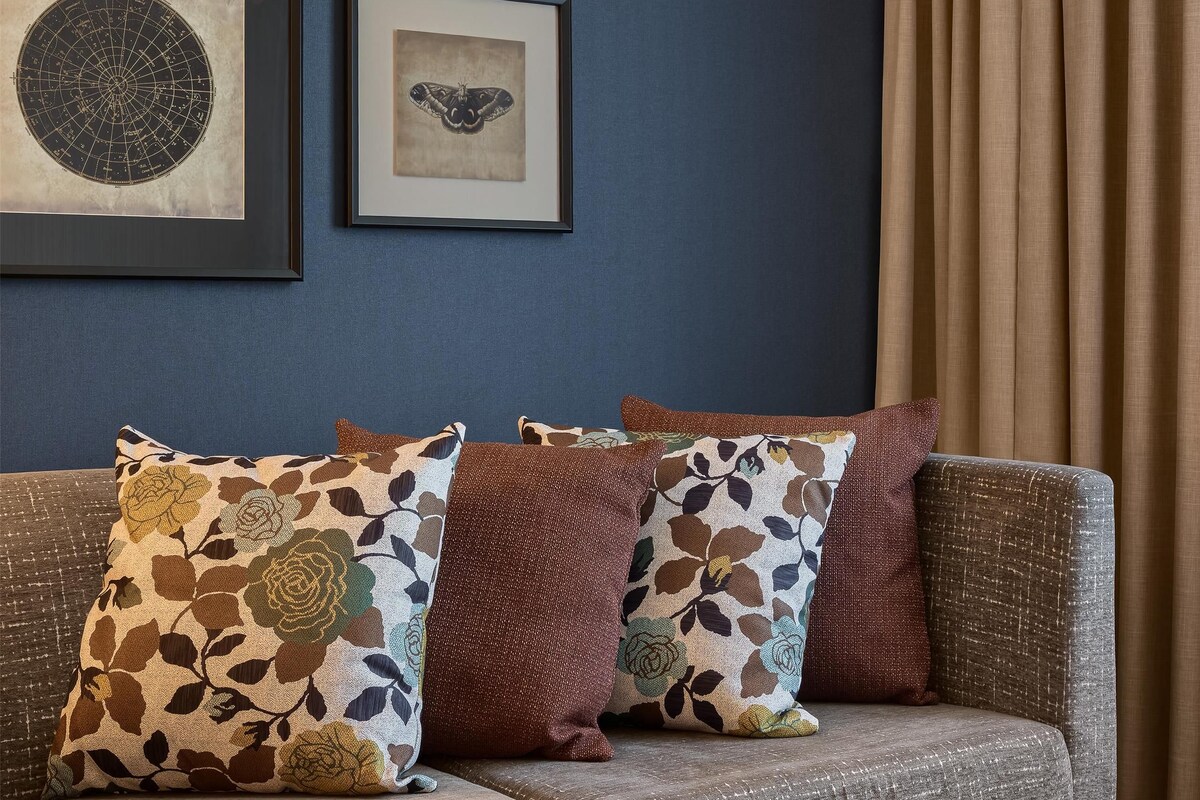 A room with a sofa, a coffee table, and two framed artworks on the wall.