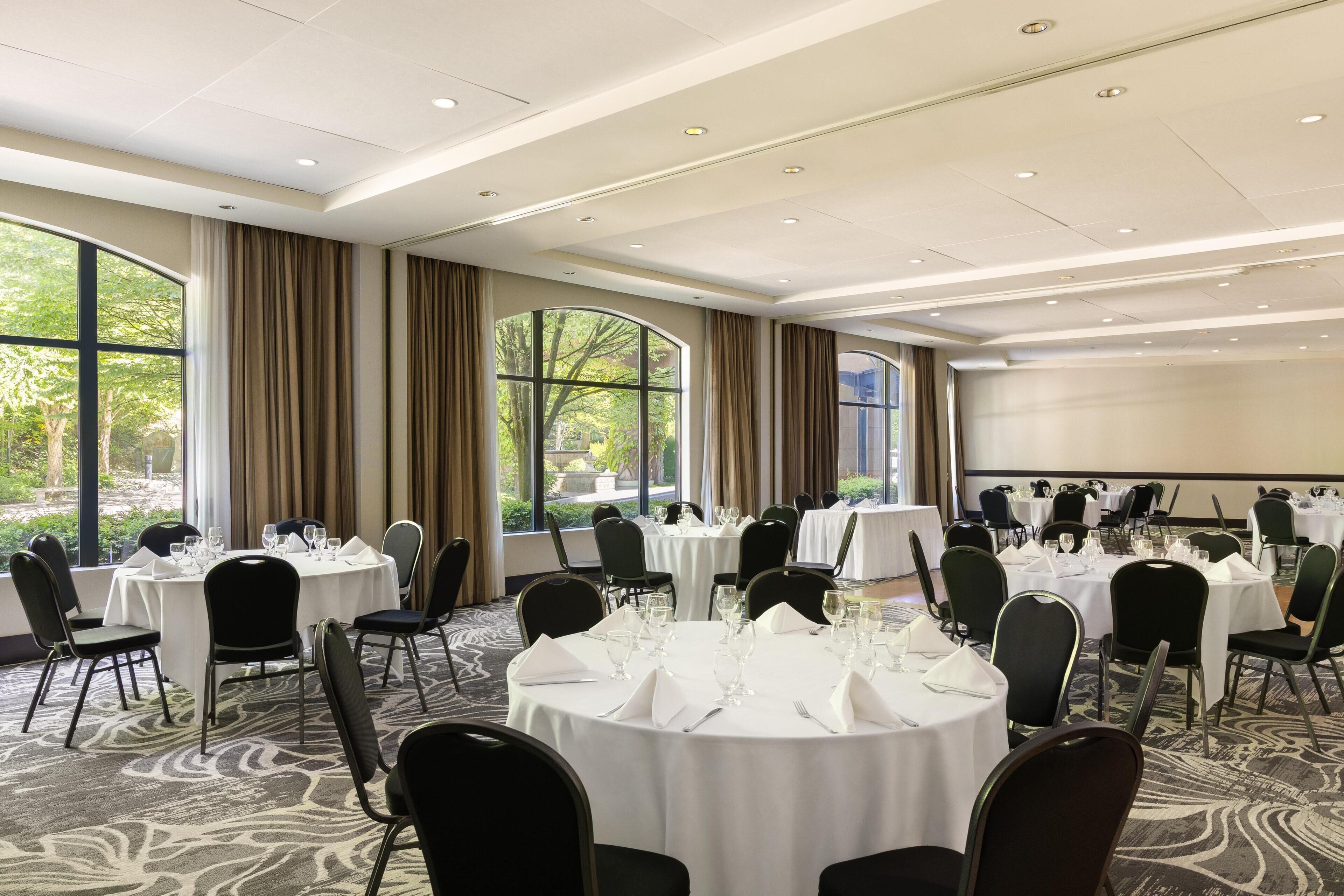 A conference room with round tables, chairs, and a projector screen.