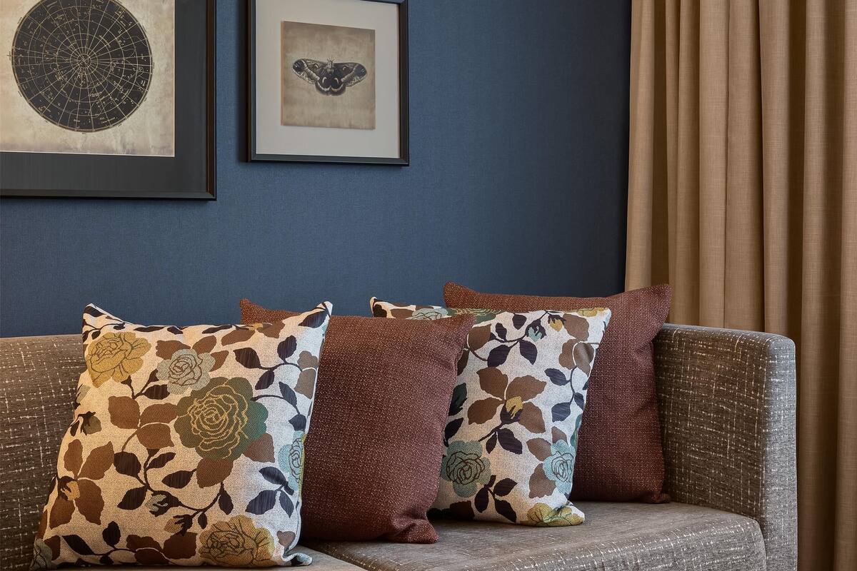 A room with a sofa, a coffee table, and two framed artworks on the wall.