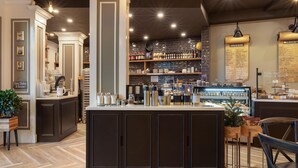Zona bar con bancone, scaffali pieni di bottiglie e lavagna dei menù.