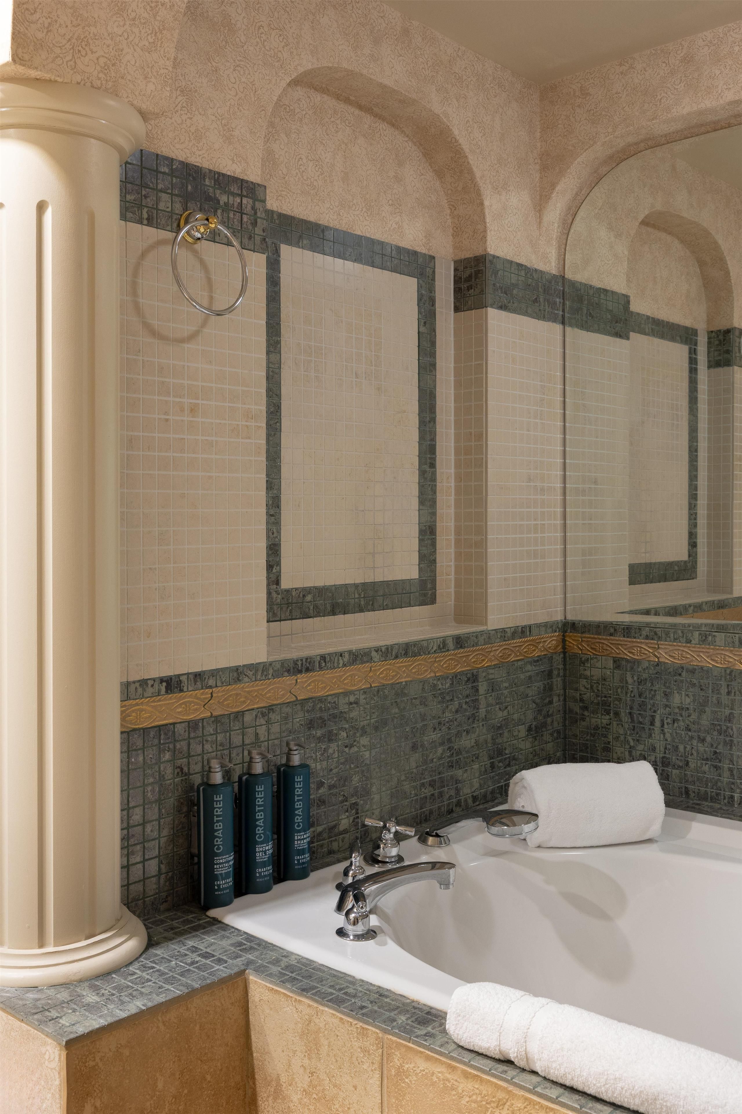 Un baño con una bañera grande, un espejo y un aro para toallas.