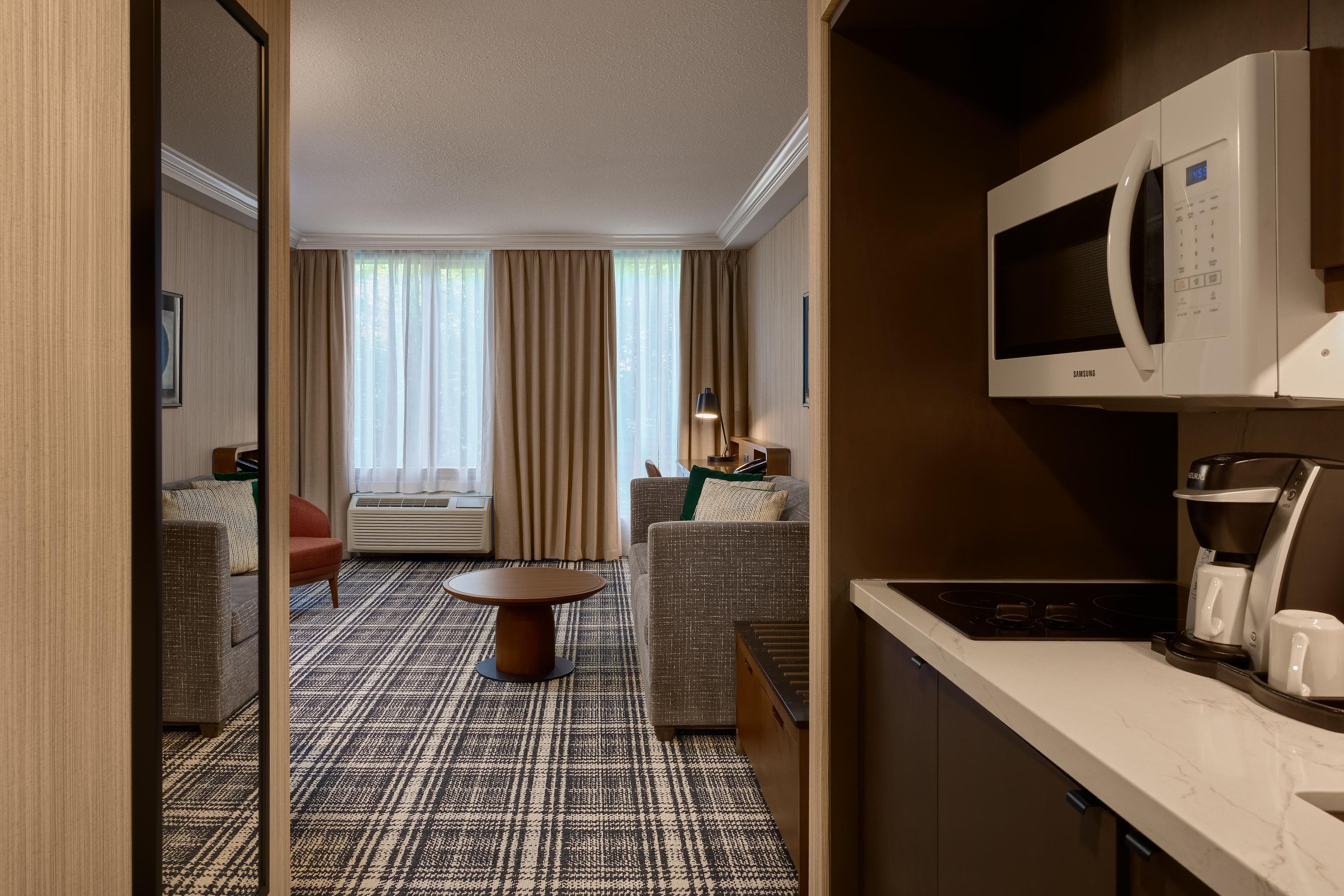 Habitación de hotel con kitchenette, sofá, mesa de comedor y vistas al exterior.