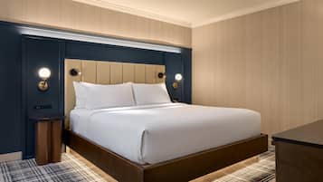 Una habitación de hotel con una cama, mesitas de noche y lámparas de pared.