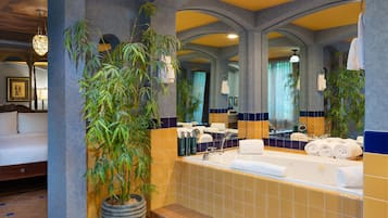 Un baño con bañera, espejos grandes y plantas en macetas.