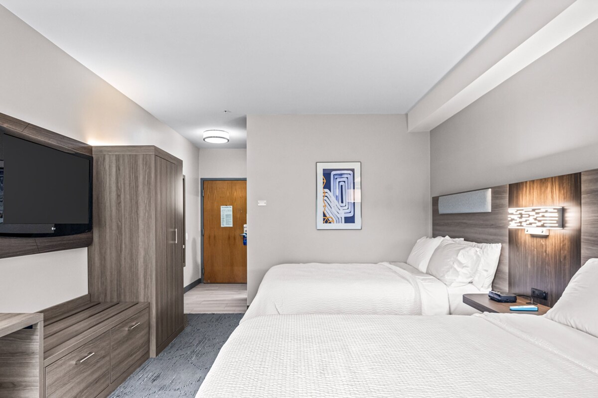 Een hotelkamer met een bed, een bureau, een televisie en een deur.