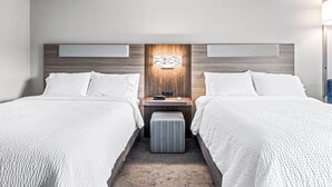A hotel room with two beds, a nightstand with a lamp, and a wall-mounted light fixture. - Holiday Inn Express Hotel & Suites Carneys Point by IHG (Penns Grove)