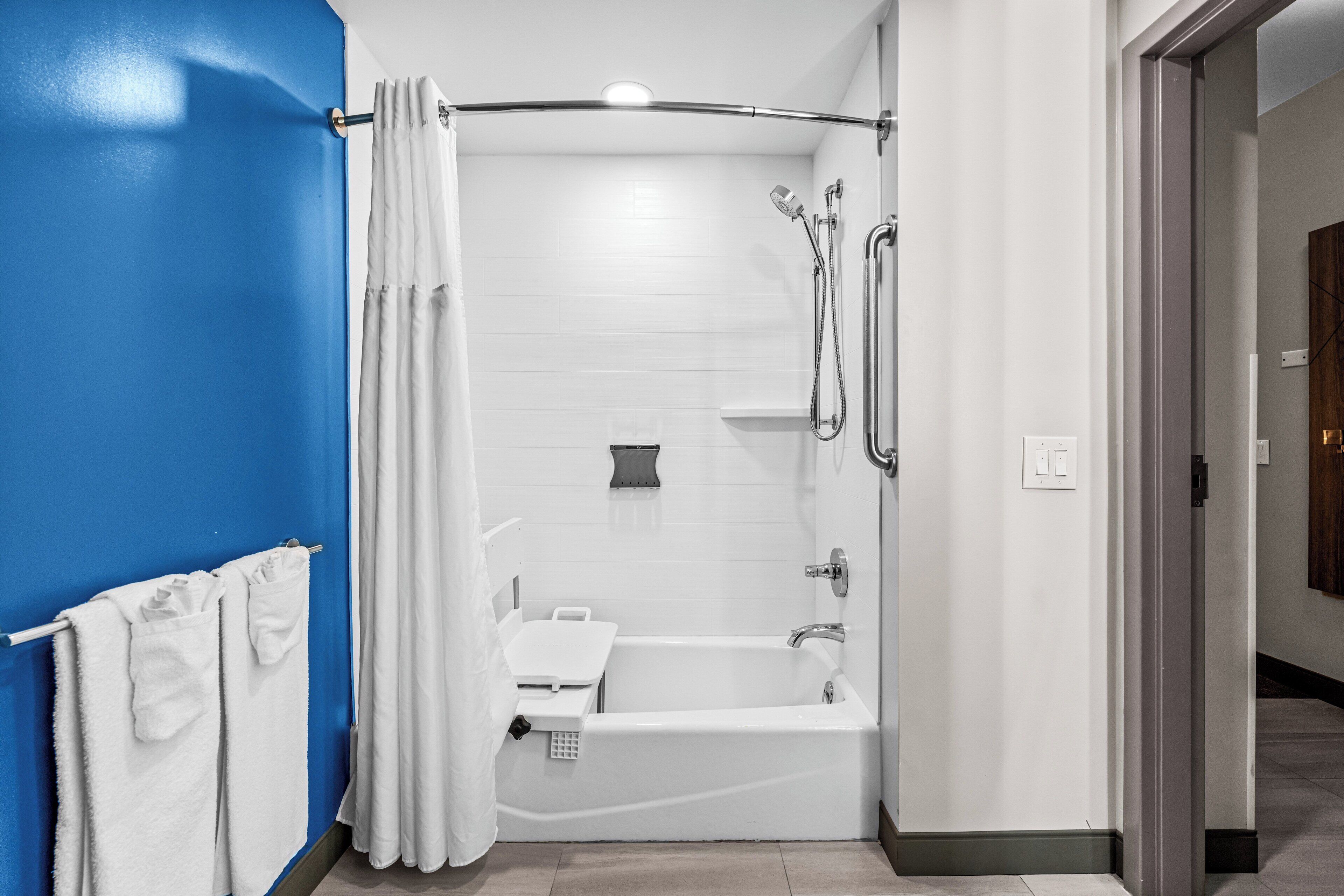A modern bathroom with a bathtub, shower, and towel rack.