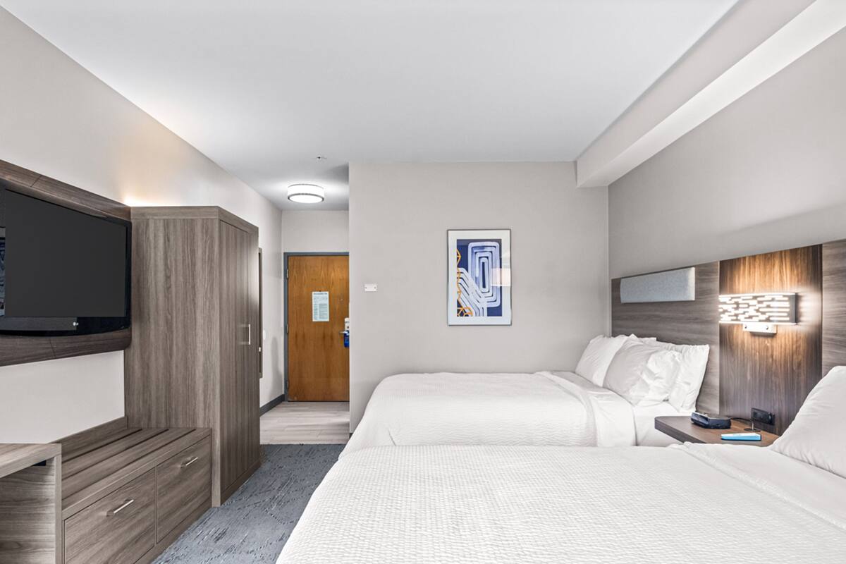 A hotel room with a bed, a desk, a TV, and a door.