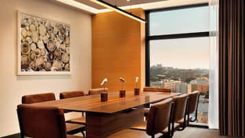 A conference room with a long table, leather chairs, a city view, and a modern light fixture.