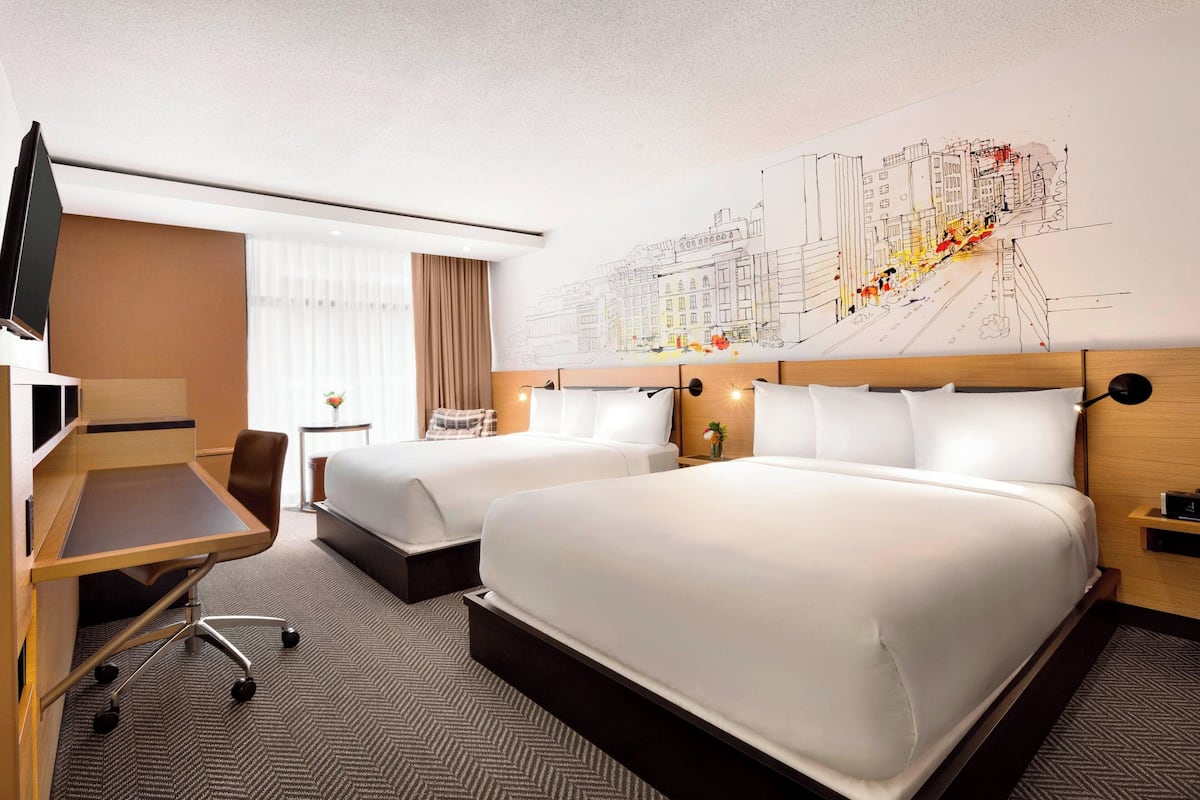 Une chambre d’hôtel avec deux lits, un bureau, une chaise, une télévision et une grande fresque murale.
