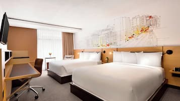 Quarto de hotel com duas camas, uma escrivaninha, uma cadeira, uma televisão e um grande mural na parede.