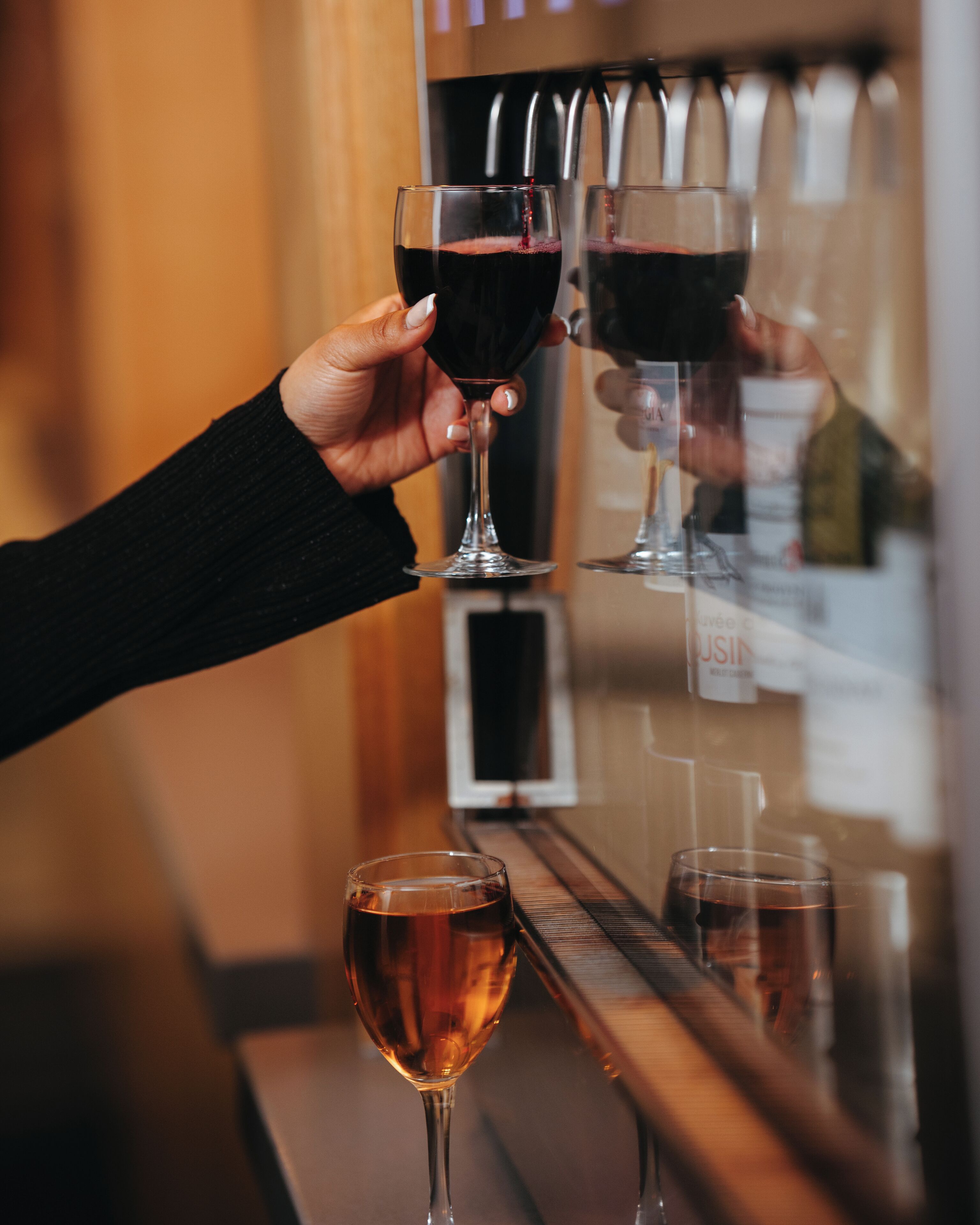A person holding two glasses of red wine and one glass of white wine.