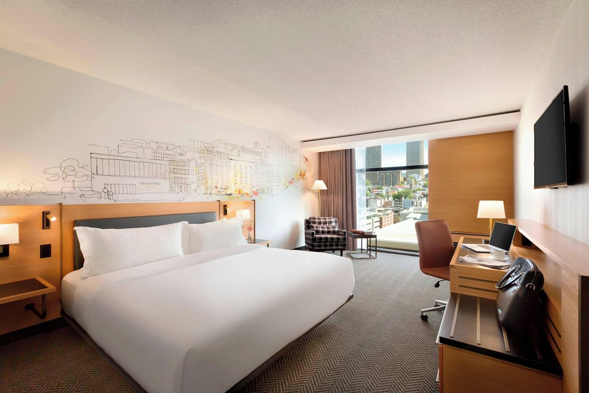 Une chambre d’hôtel avec un grand lit, un bureau avec un ordinateur, une chaise et un téléviseur.