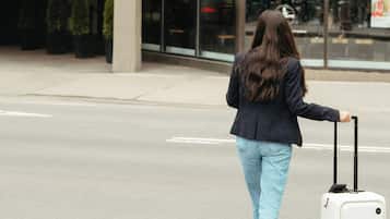Una mujer caminando hacia un edificio con un letrero que dice "TEL PUR" y "CAFÉ VAN HOUTT".
