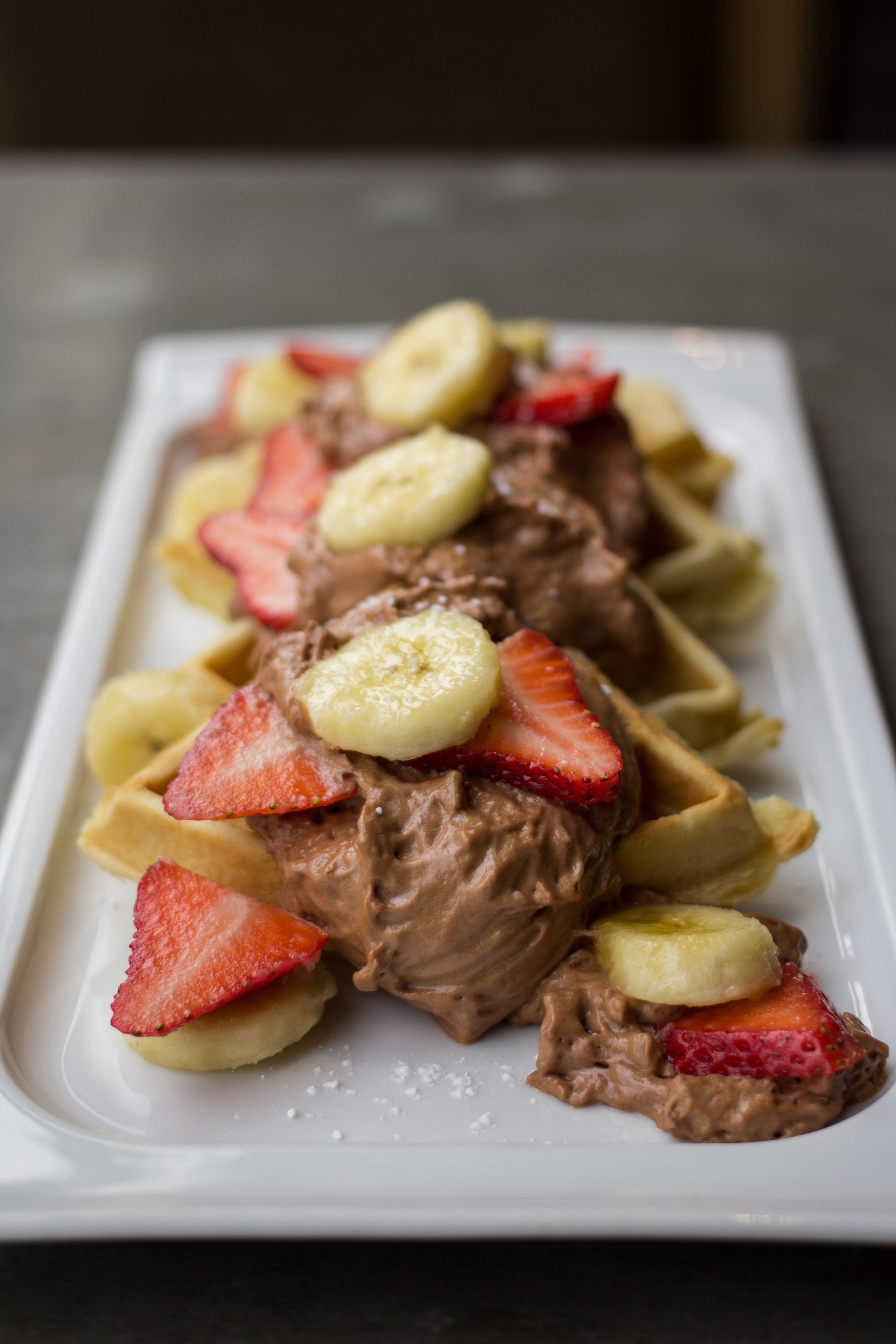A dessert plate with chocolate ice cream and banana slices on a white plate.