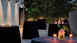 Round tables with black tablecloths, candles, and floral centerpieces.