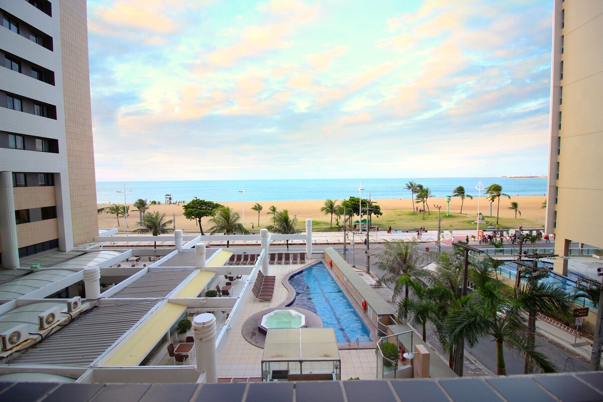 A rooftop pool area with a view of the beach and ocean.