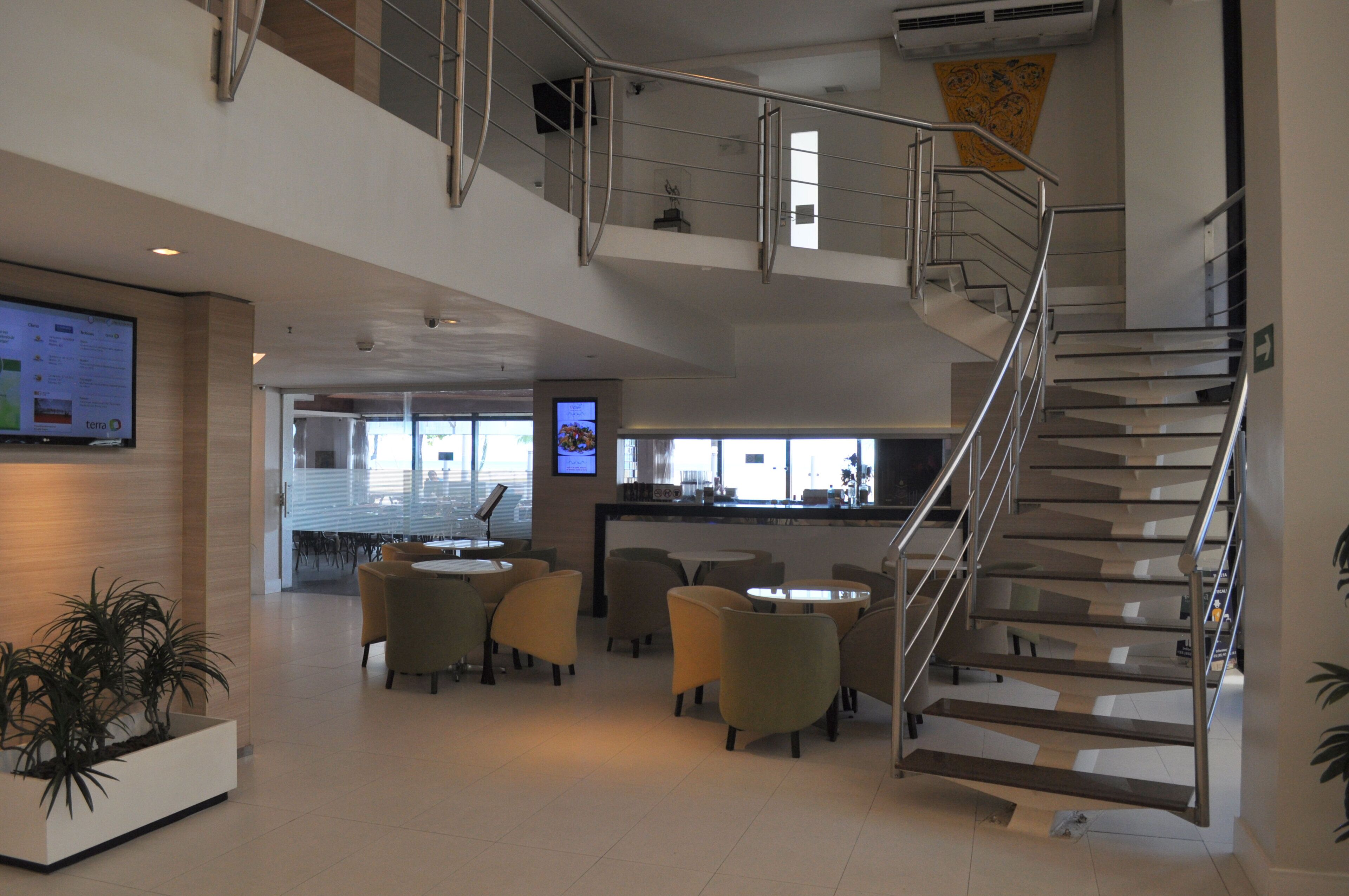 A modern interior with a staircase, seating area, and a digital display.