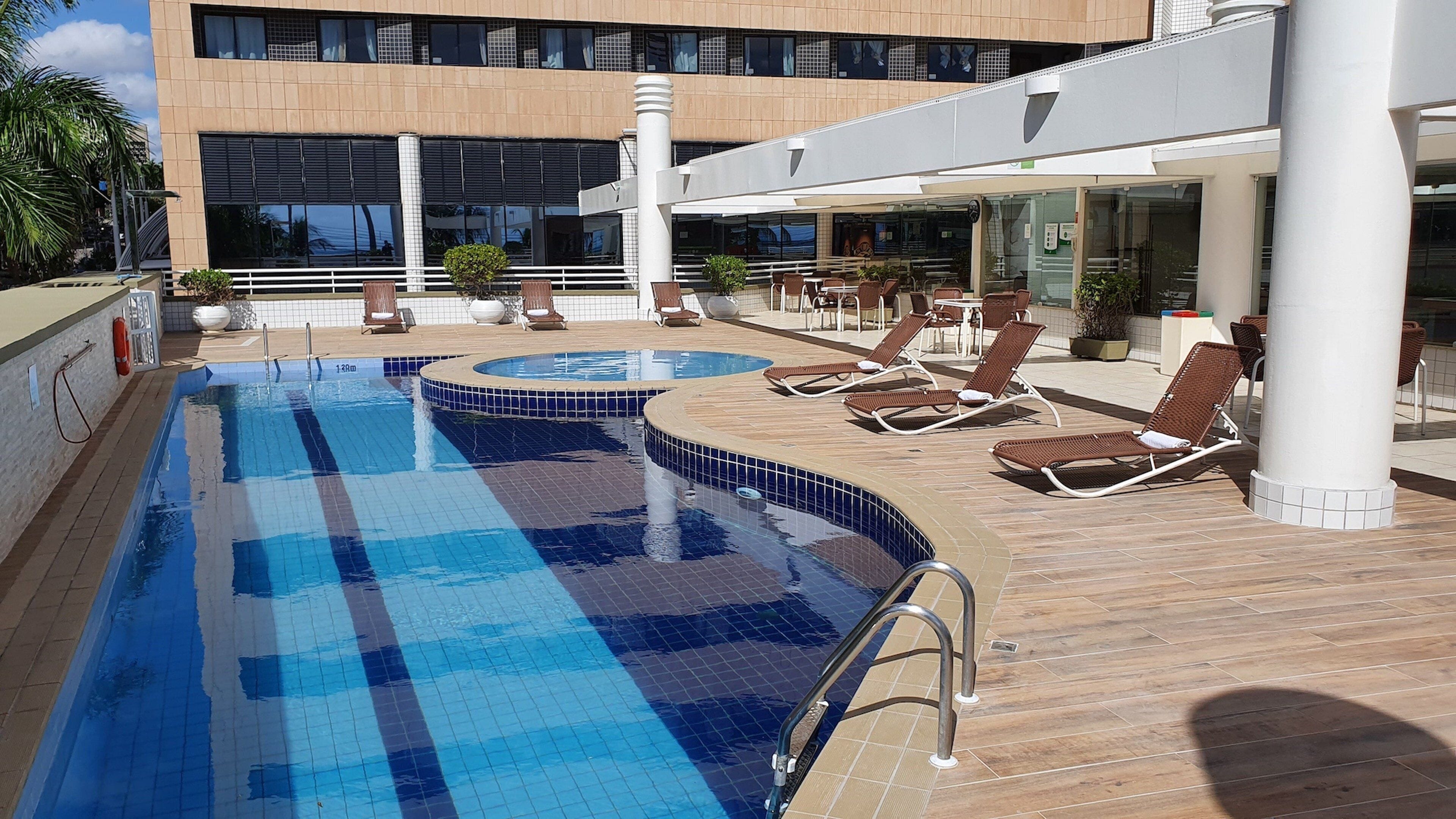 A swimming pool with lounge chairs and a building in the background.