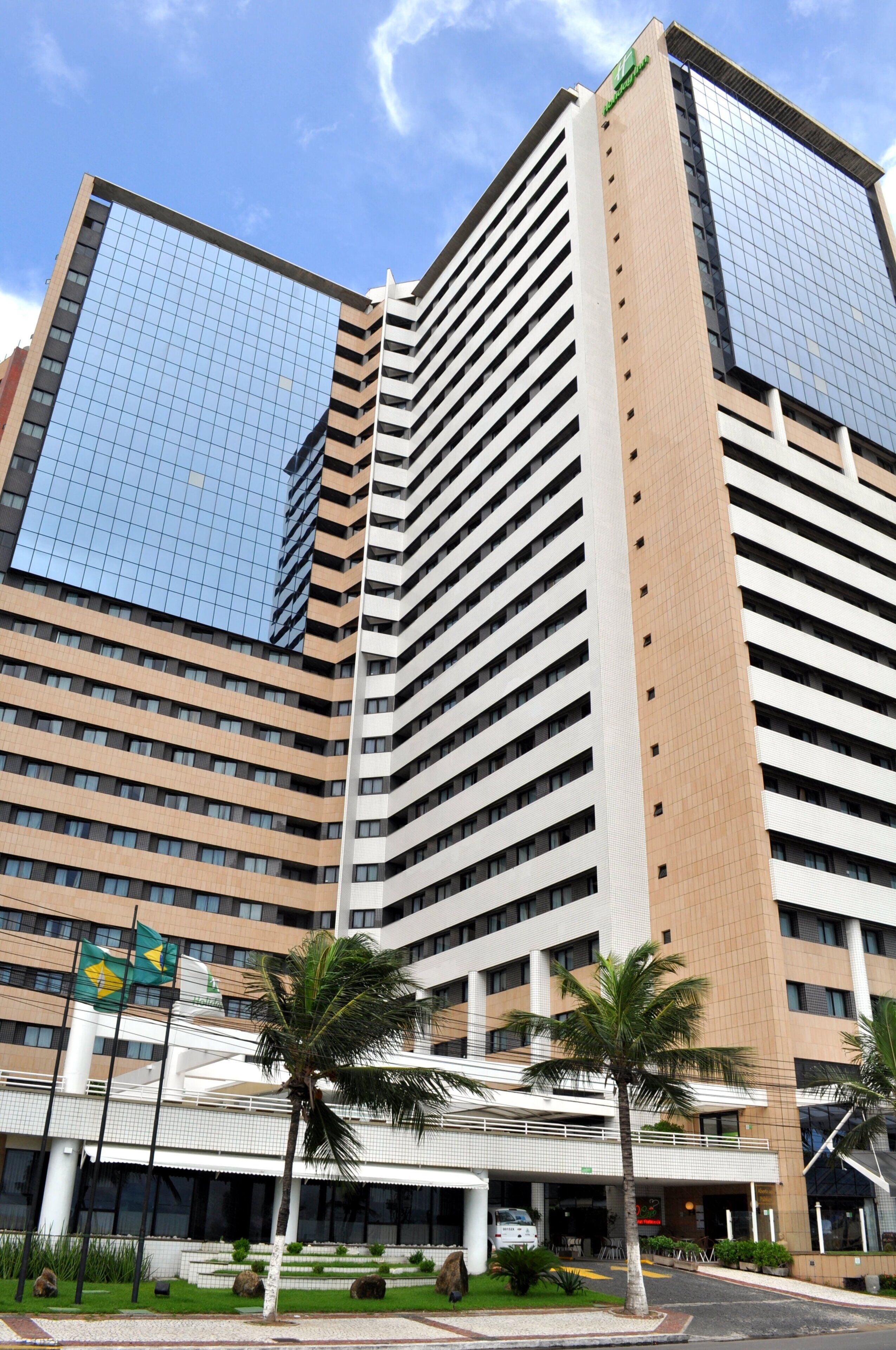 A multi-story hotel with a modern architectural design, featuring a prominent glass facade and a series of balconies.