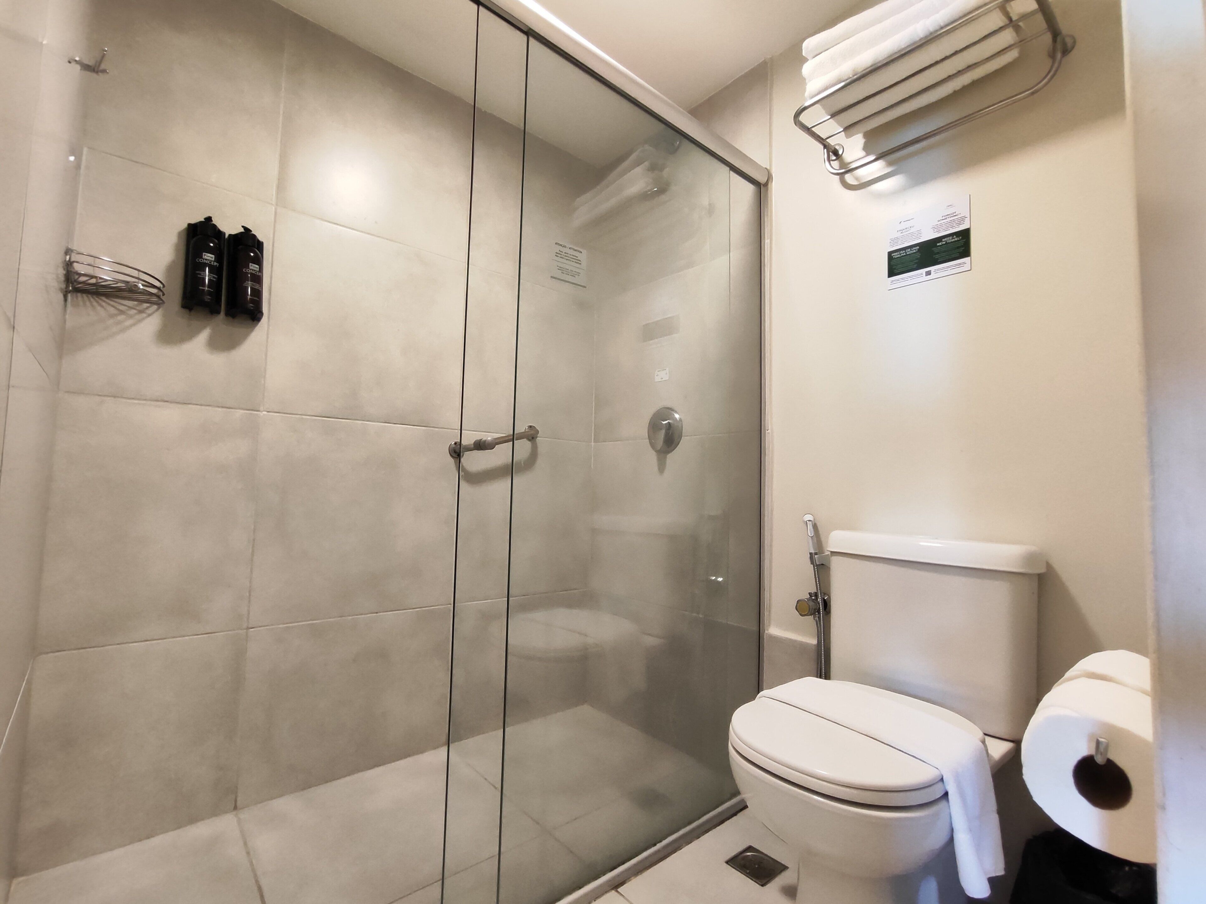 A modern bathroom with a glass-enclosed shower, a toilet, and a towel rack.