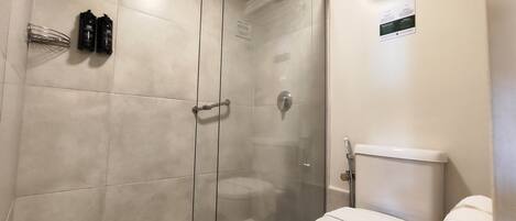 A modern bathroom with a glass-enclosed shower, a toilet, and a towel rack.