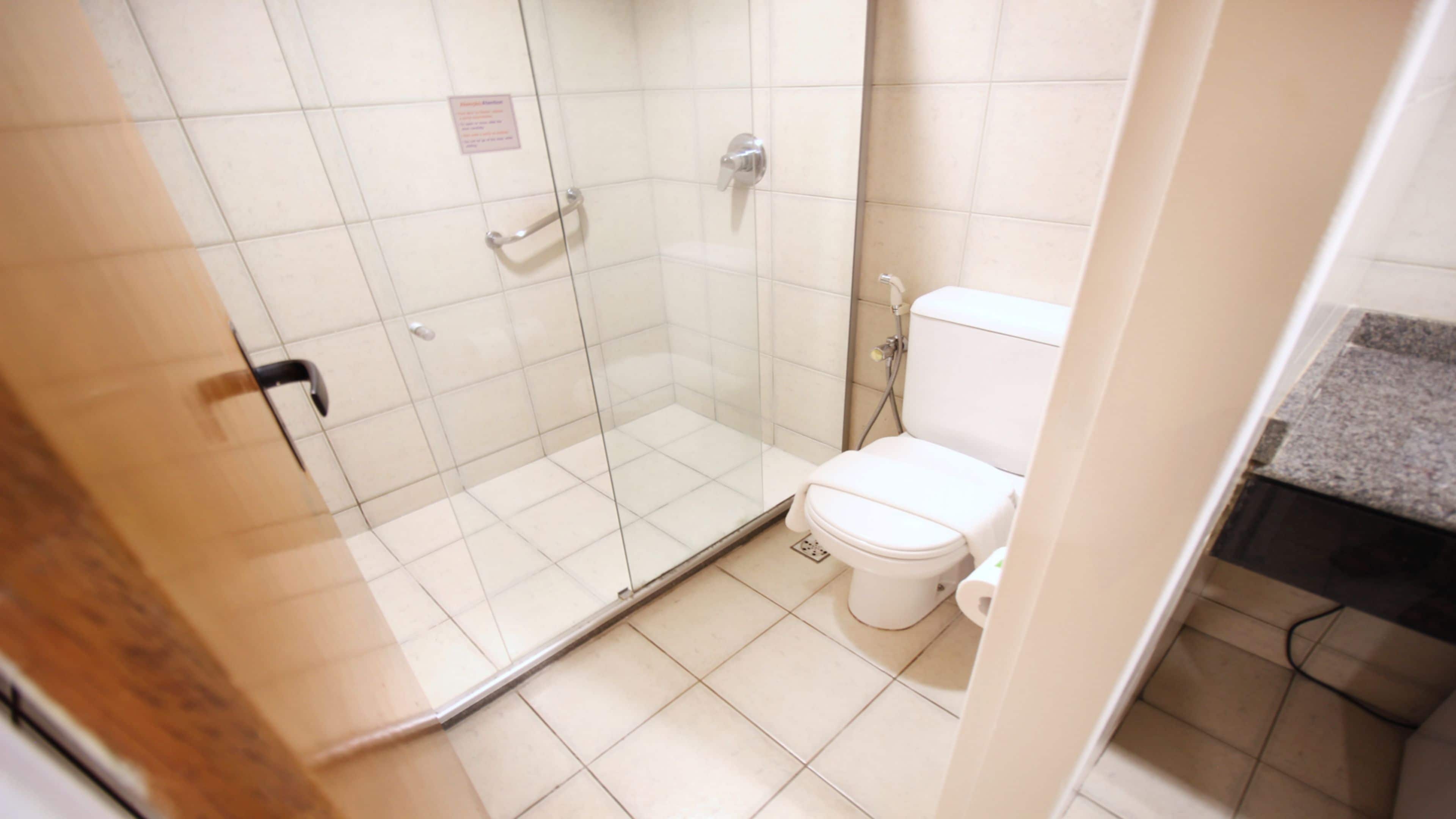 Un baño con cabina de ducha de vidrio, inodoro y lavamanos.