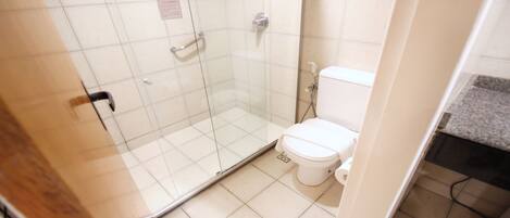 Un baño con cabina de ducha de vidrio, inodoro y lavamanos.