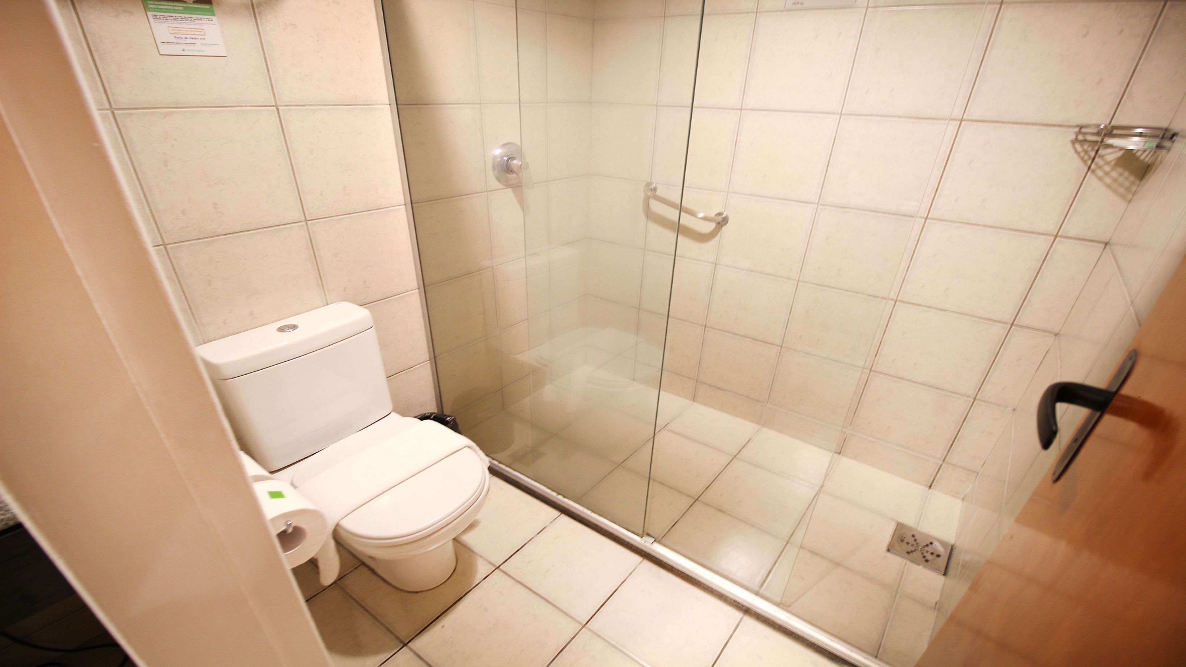 A bathroom with a toilet, a glass shower enclosure, and a tiled floor.