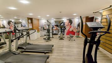 Un gimnasio con cintas de correr, elípticas y equipo de levantamiento de pesas.