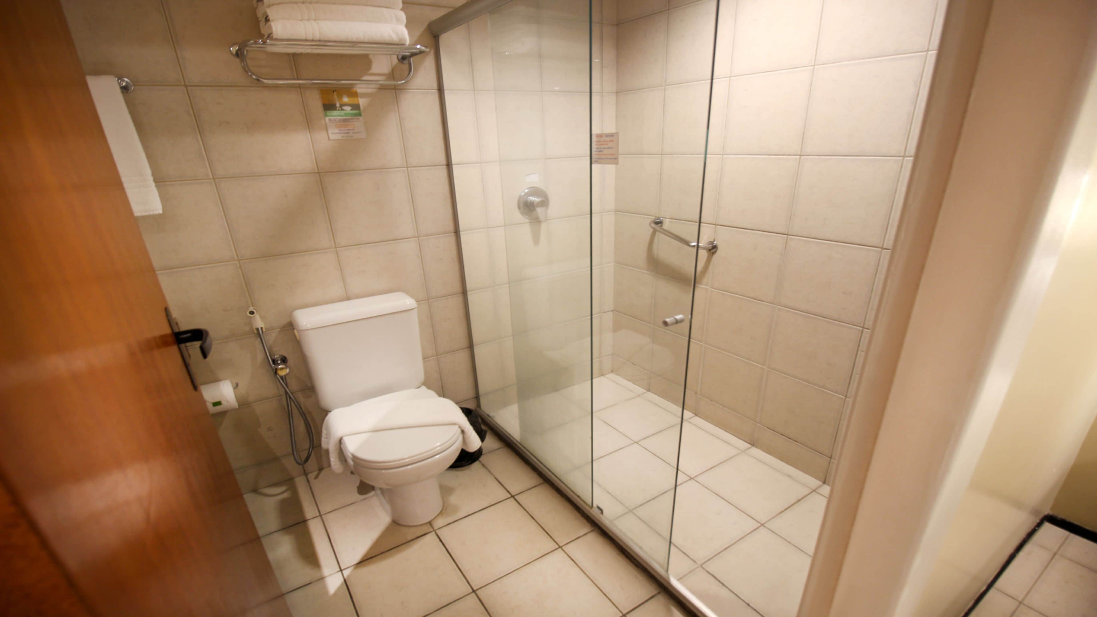 Et badeværelse med toilet, brusekabine og bøjle til håndklæder.