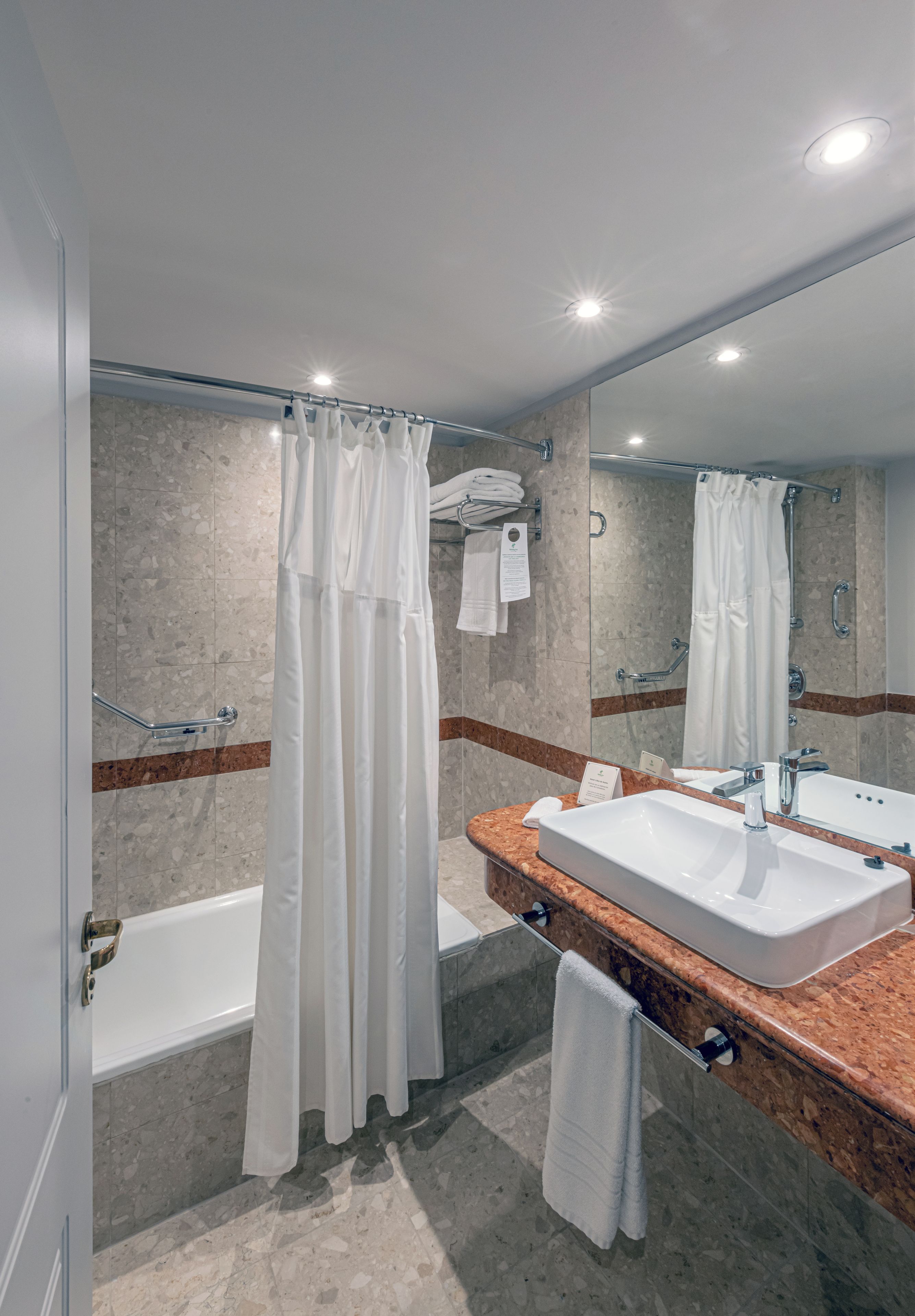 A modern bathroom with a bathtub, a large mirror, and a marble countertop.
