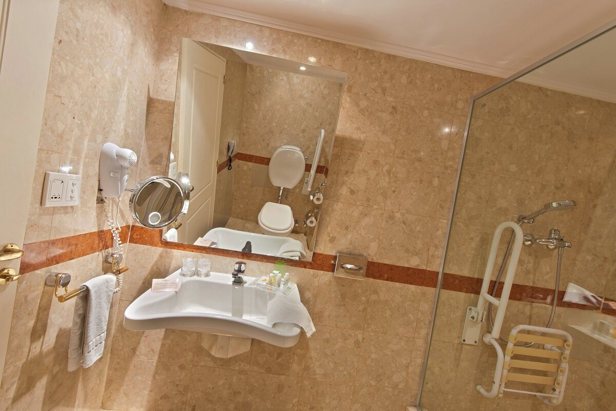 A bathroom with a sink, mirror, toilet, and shower.