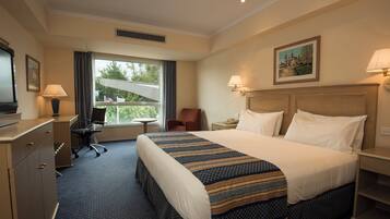 A hotel room with a bed, desk, chair, and a window with a view.
