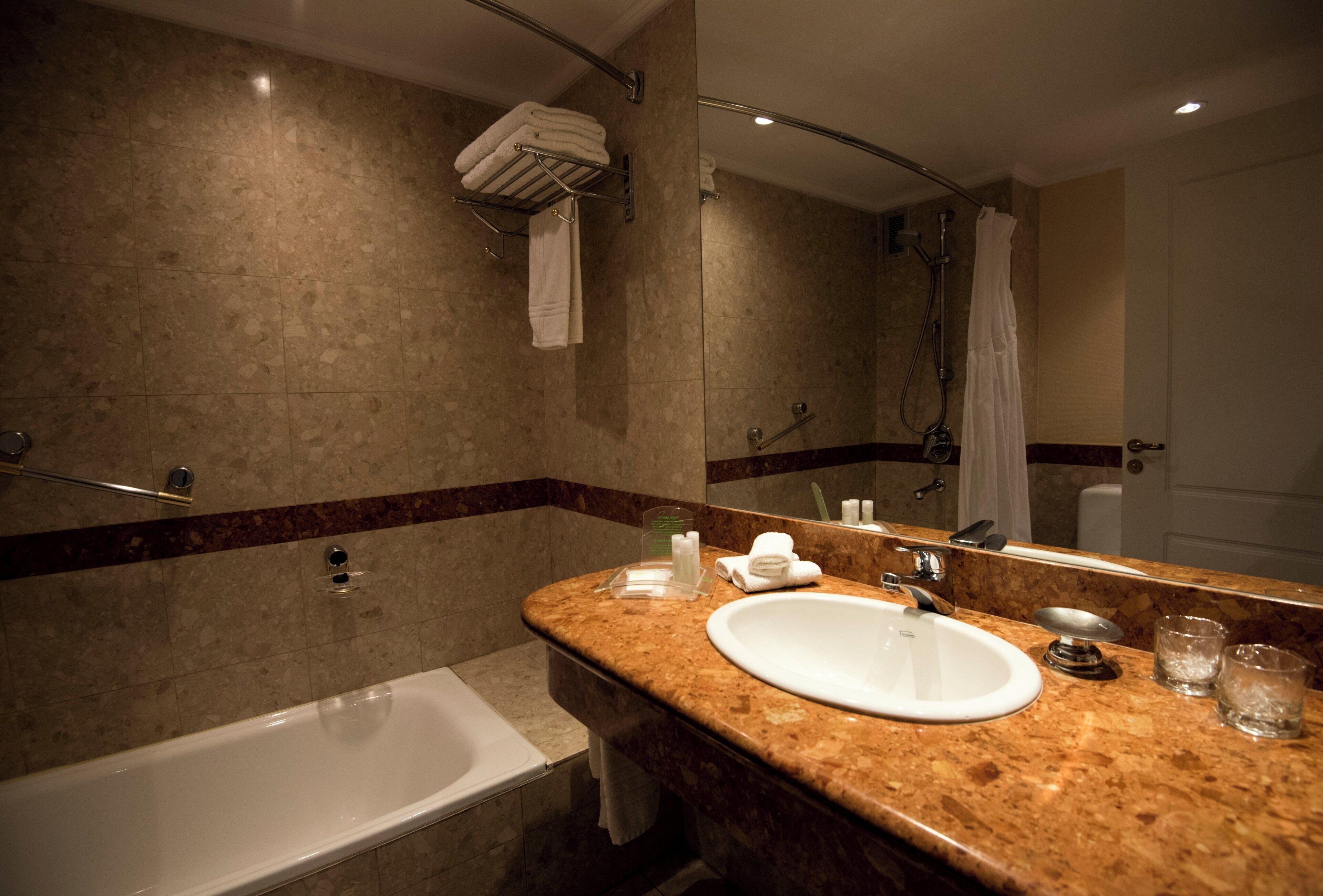 A bathroom with a bathtub, a sink, a mirror, and a shower.