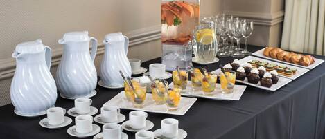 A buffet table with various food items, including fruit cups, pastries, and a pitcher of iced tea.