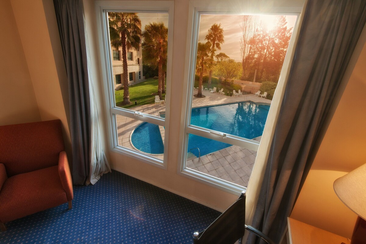 Habitación con vista a una piscina y un césped.