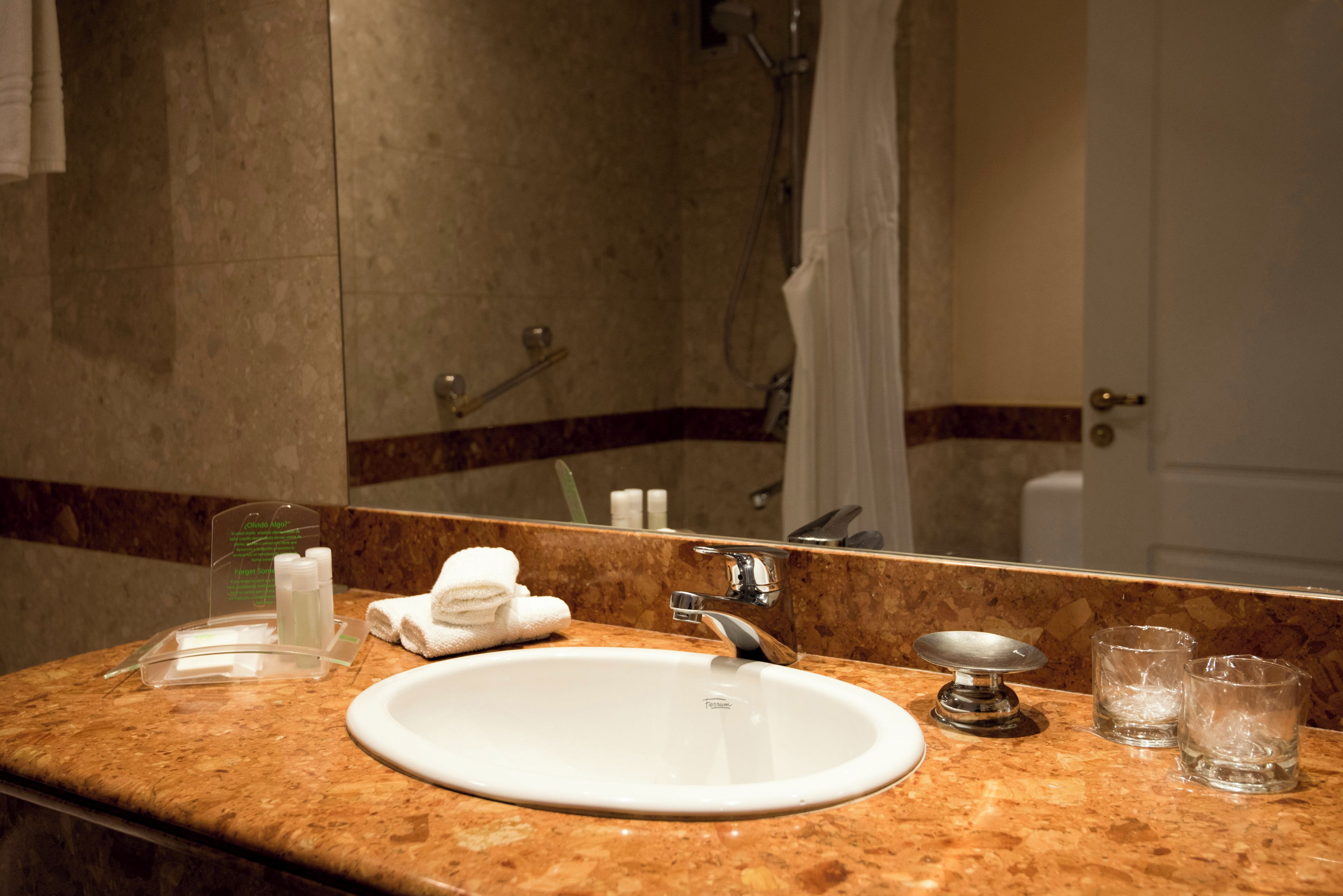 A bathroom with a sink, mirror, shower, and towel rack.