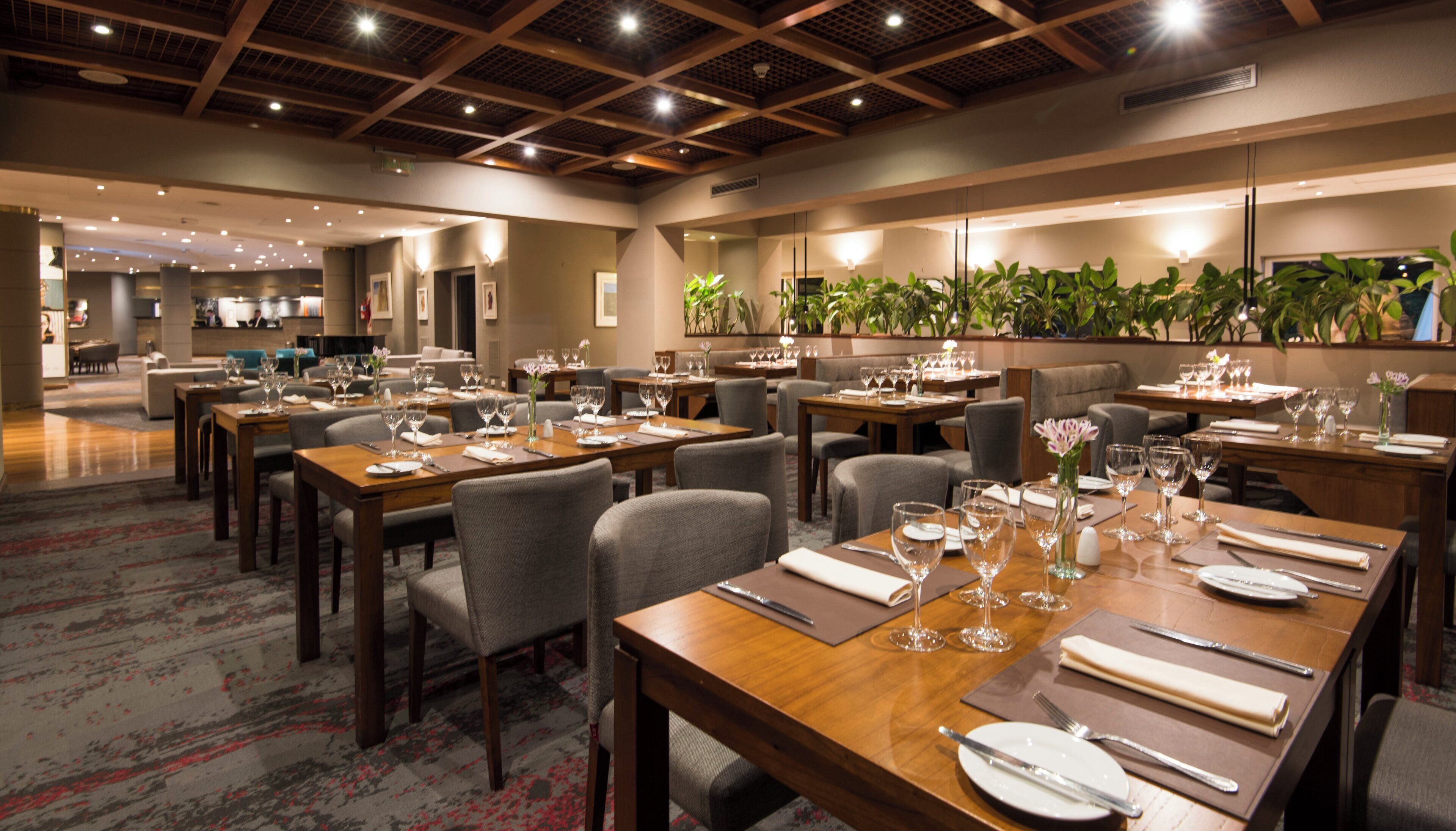 A hotel dining area with multiple tables set for dining, chairs, and a variety of table settings.