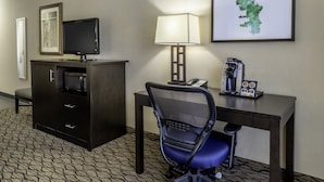 A hotel room with a desk, chair, television, lamp, coffee maker, and a minibar. - Holiday Inn Hotel & Suites-Milwaukee Airport by IHG (Milwaukee)