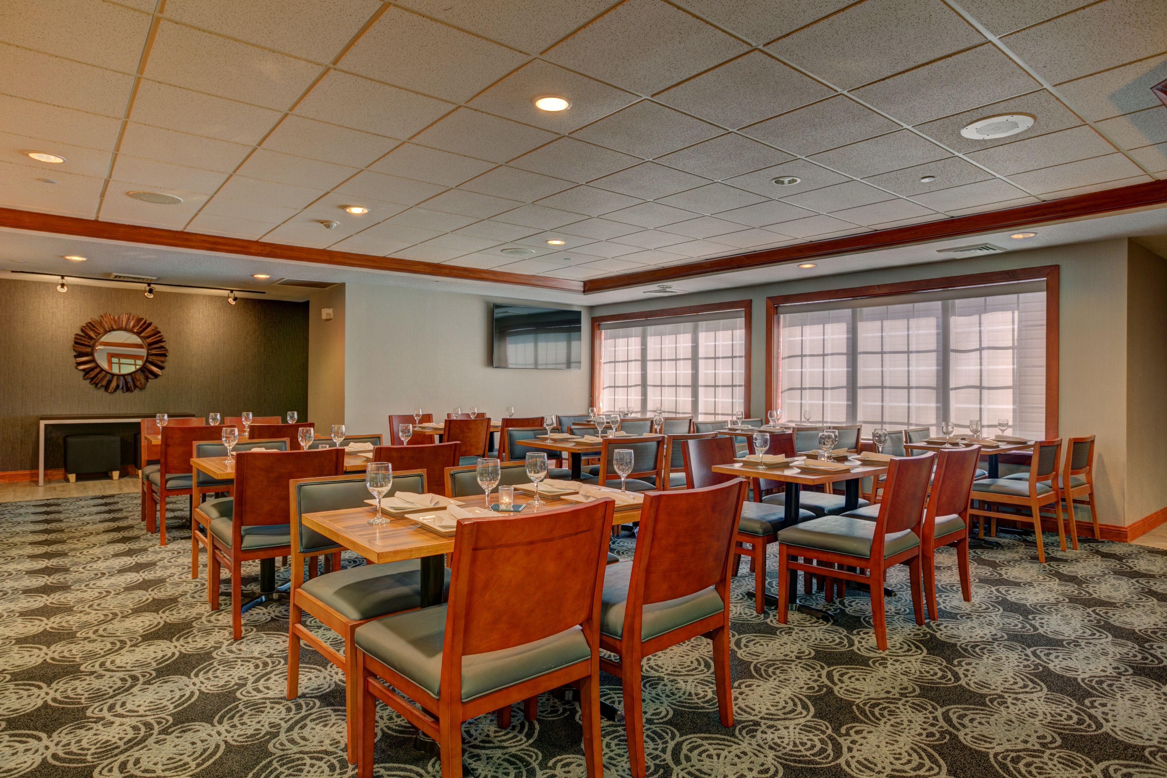 A conference room with multiple tables and chairs, large windows, and a patterned carpet.