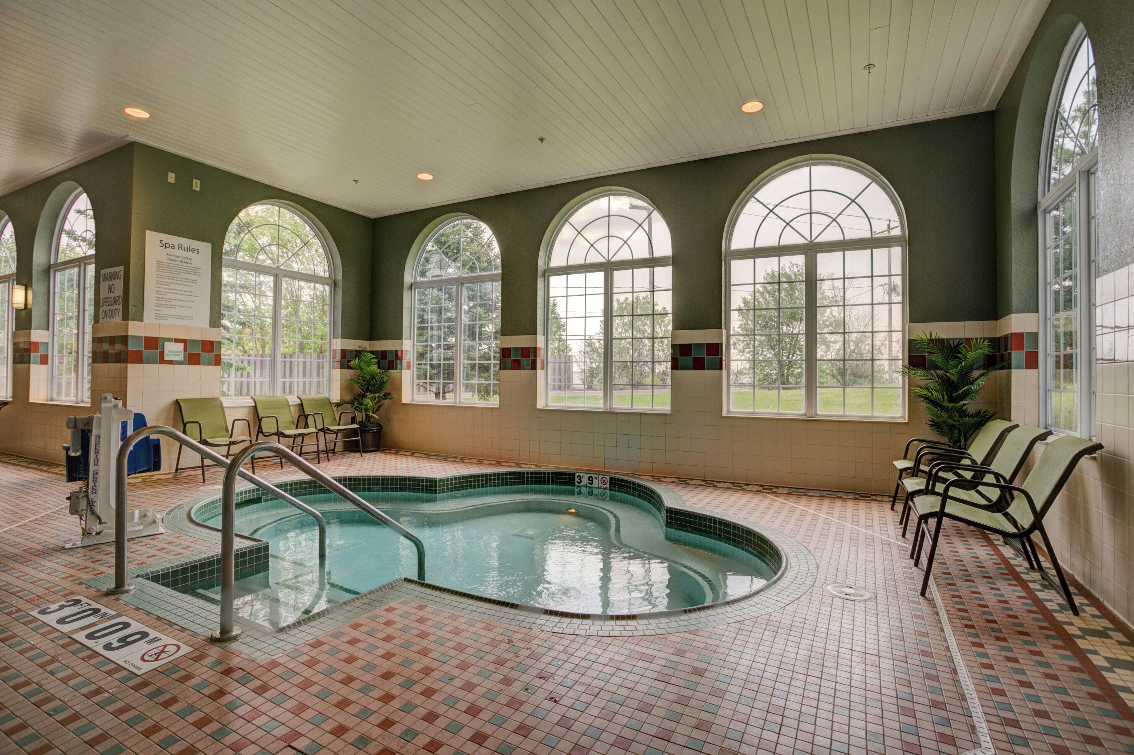 Ein Poolbereich mit Whirlpool, Liegestühlen und gefliestem Boden.